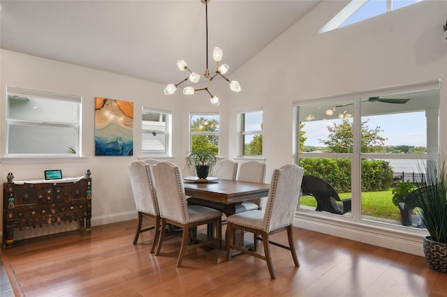 dining room with an inviting chandelier, wood-type flooring, high vaulted ceiling, and a healthy amount of sunlight