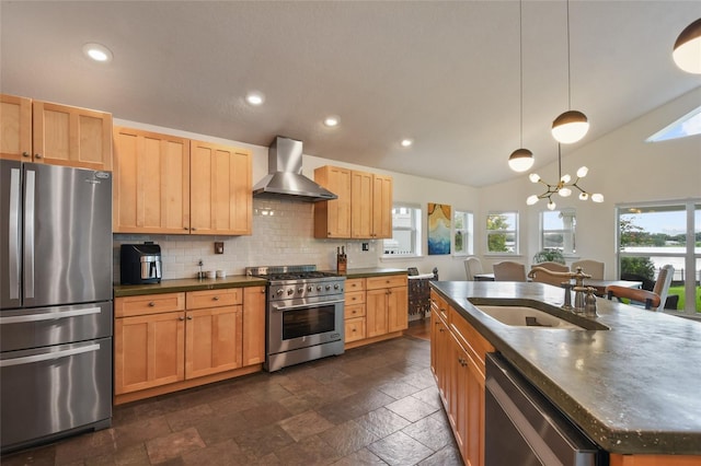 kitchen featuring decorative light fixtures, sink, stainless steel appliances, a center island with sink, and wall chimney exhaust hood