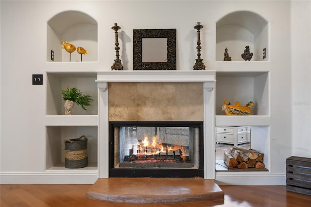 details featuring a multi sided fireplace, wood-type flooring, and built in features