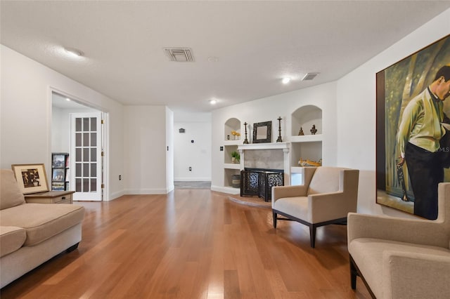 living room featuring wood-type flooring and built in shelves