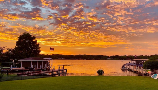 view of dock with a gazebo, a water view, and a lawn