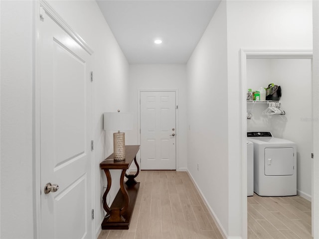 doorway to outside with light hardwood / wood-style flooring and washing machine and dryer