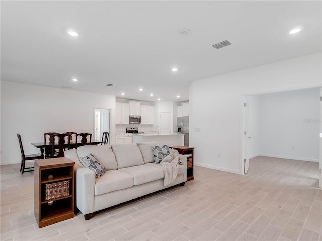 living room featuring sink and light hardwood / wood-style flooring