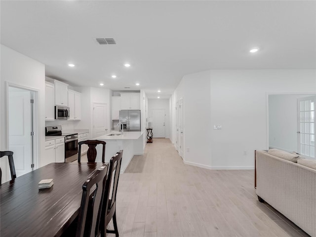 dining space with sink and light hardwood / wood-style floors