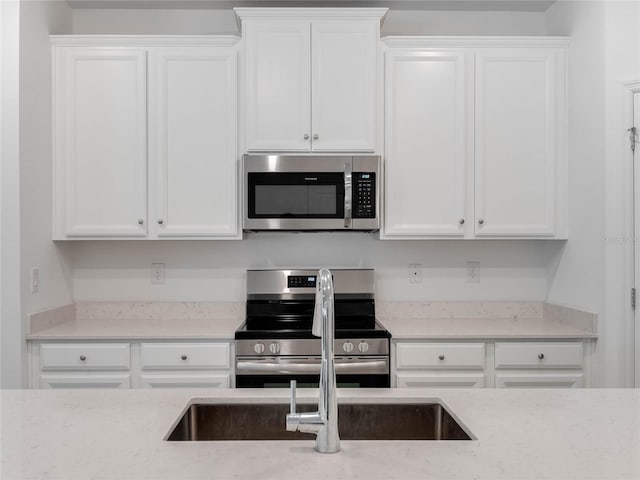 kitchen with stainless steel appliances, sink, and white cabinets