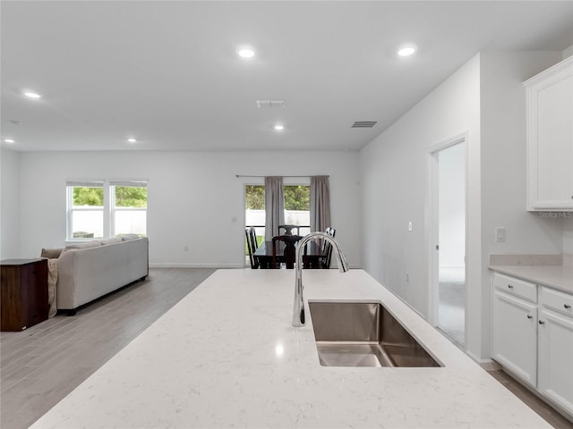 kitchen with white cabinetry, plenty of natural light, sink, and light stone counters