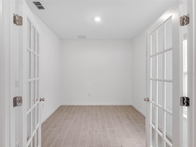 unfurnished room with french doors and light hardwood / wood-style flooring