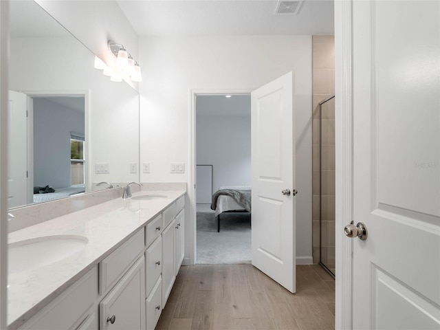 bathroom with hardwood / wood-style flooring, vanity, and an enclosed shower