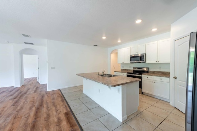 2950 Gibraltar Blvd, New Smyrna Beach, FL 32168 - kitchen featuring visible vents, a sink, arched walkways, a center island with sink, and appliances with stainless steel finishes
