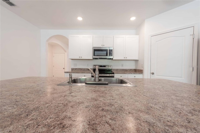 2950 Gibraltar Blvd, New Smyrna Beach, FL 32168 - kitchen with arched walkways, visible vents, white cabinetry, and stainless steel appliances
