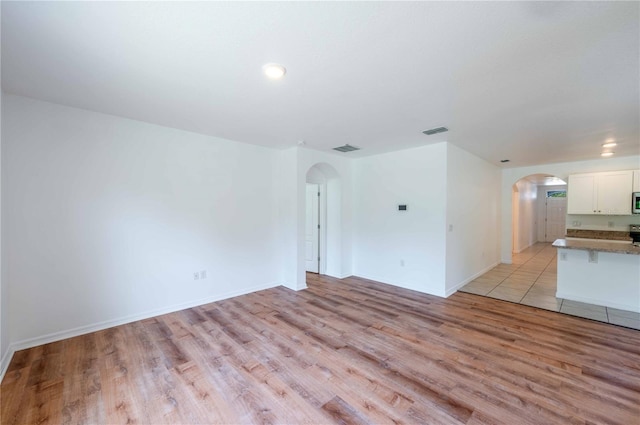 2950 Gibraltar Blvd, New Smyrna Beach, FL 32168 - unfurnished living room featuring light wood-style flooring, visible vents, and arched walkways