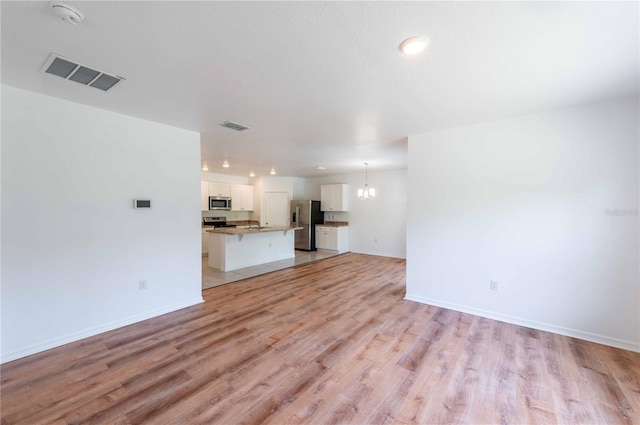2950 Gibraltar Blvd, New Smyrna Beach, FL 32168 - unfurnished living room featuring light wood-type flooring, baseboards, visible vents, and a notable chandelier