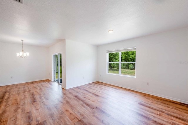 2950 Gibraltar Blvd, New Smyrna Beach, FL 32168 - spare room with baseboards, a chandelier, a textured ceiling, and light wood-type flooring