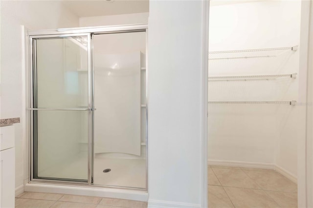 2950 Gibraltar Blvd, New Smyrna Beach, FL 32168 - bathroom featuring tile patterned floors, baseboards, a shower stall, and a walk in closet