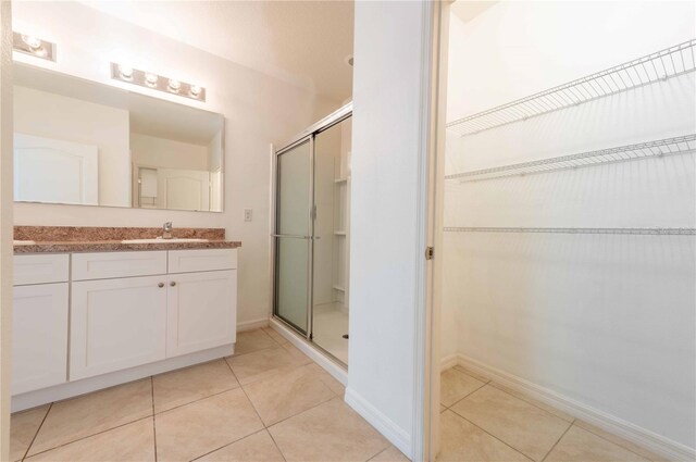 2950 Gibraltar Blvd, New Smyrna Beach, FL 32168 - bathroom featuring tile patterned flooring, vanity, a spacious closet, and a shower stall