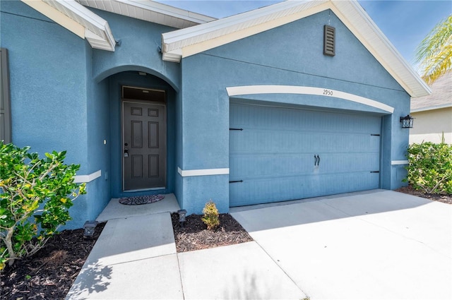 2950 Gibraltar Blvd, New Smyrna Beach, FL 32168 - doorway to property with an attached garage, concrete driveway, and stucco siding