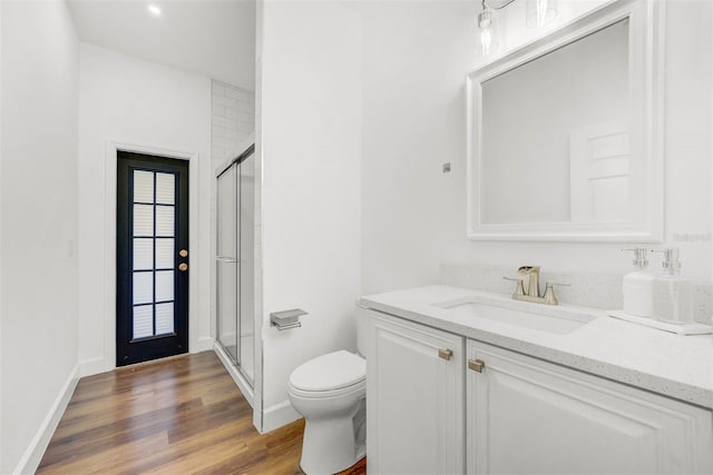 bathroom with hardwood / wood-style flooring, vanity, toilet, and an enclosed shower