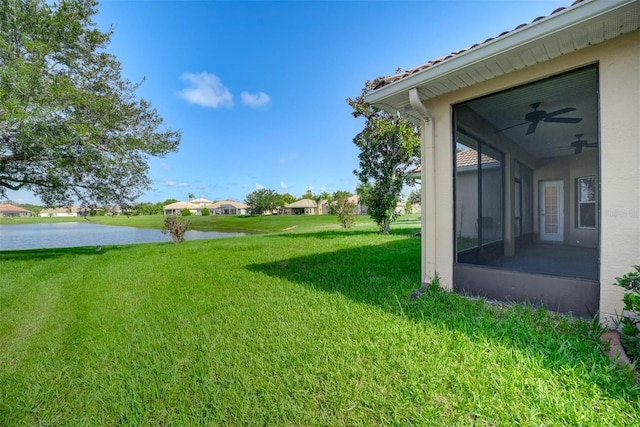 view of yard featuring a water view, ceiling fan, and a sunroom