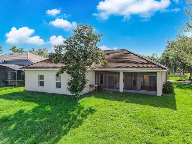 rear view of house with a sunroom and a lawn