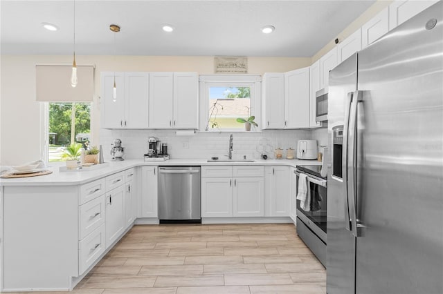 kitchen with decorative backsplash, white cabinetry, appliances with stainless steel finishes, and sink