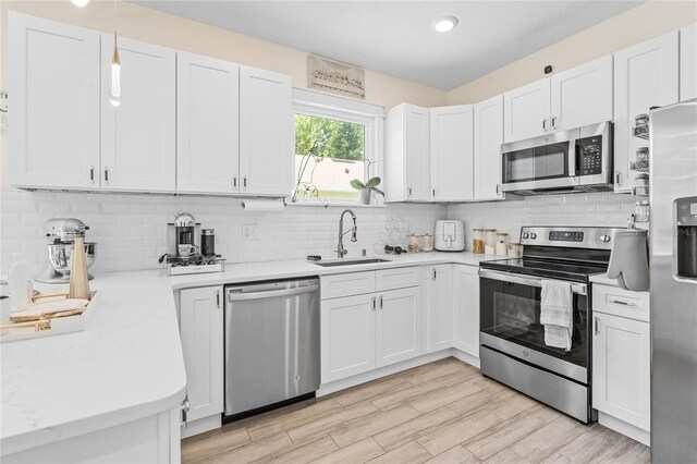 kitchen featuring appliances with stainless steel finishes, white cabinetry, backsplash, and sink