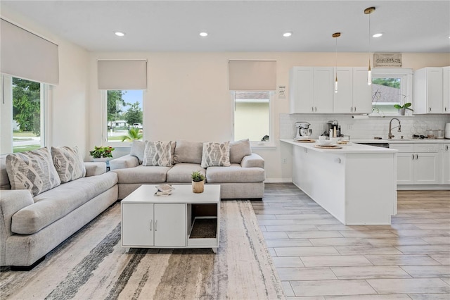 living room featuring sink, light wood-type flooring, and a healthy amount of sunlight