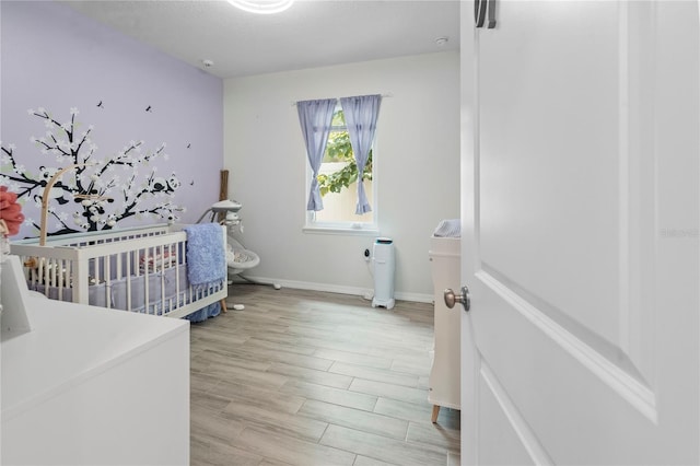 bedroom featuring a crib and light wood-type flooring