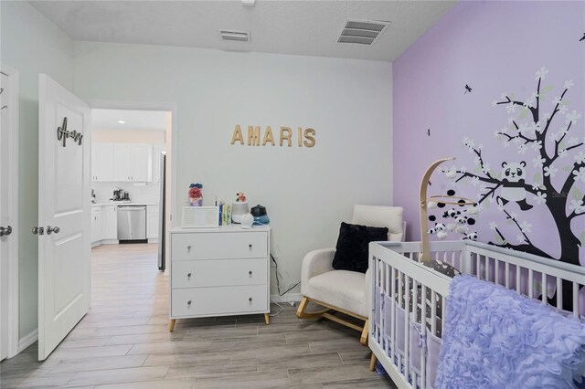 bedroom featuring light hardwood / wood-style floors and a nursery area