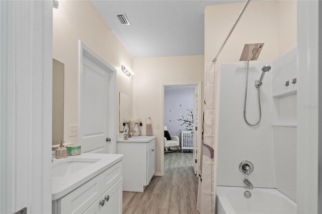 bathroom with vanity, hardwood / wood-style floors, a textured ceiling, and shower / tub combo