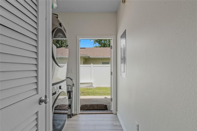 doorway to outside with light hardwood / wood-style floors and stacked washer / dryer