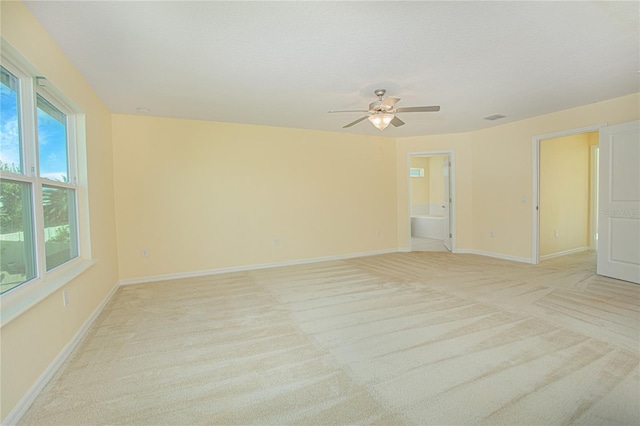 spare room with ceiling fan, light colored carpet, and a healthy amount of sunlight