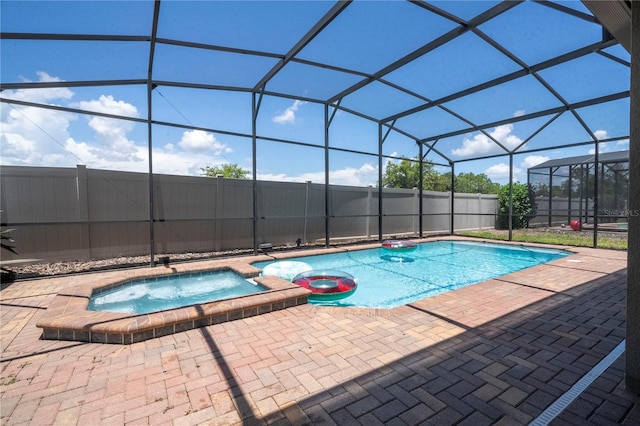 view of pool with a patio, an in ground hot tub, and glass enclosure