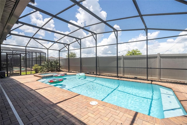 view of pool with an in ground hot tub, a patio, and glass enclosure