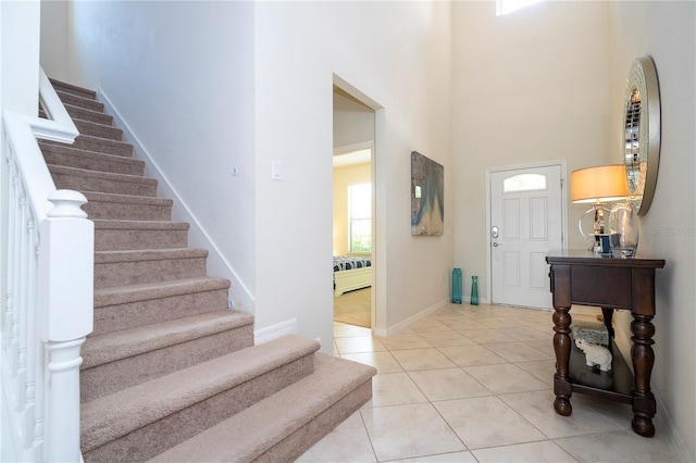 entryway with light tile patterned flooring and a towering ceiling