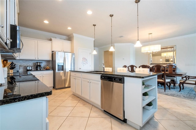 kitchen featuring appliances with stainless steel finishes, pendant lighting, decorative backsplash, and a kitchen island with sink