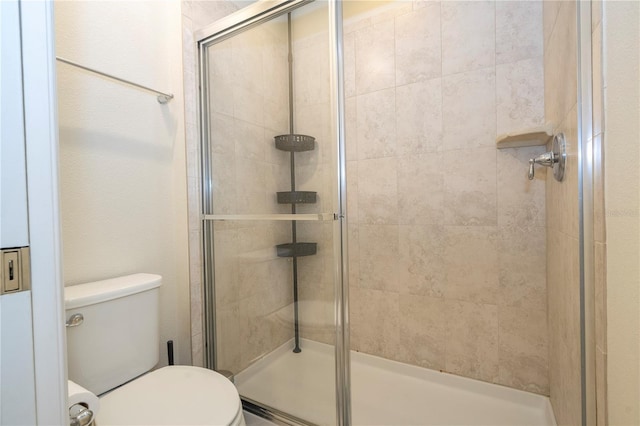 bathroom with a shower with shower door and toilet