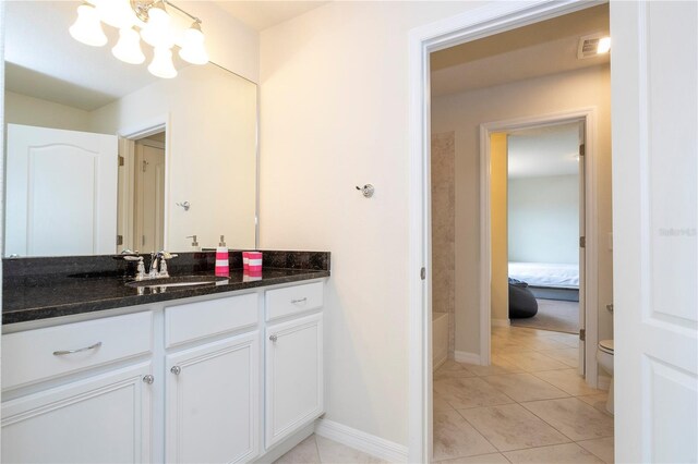 bathroom with vanity, tile patterned flooring, toilet, and a chandelier