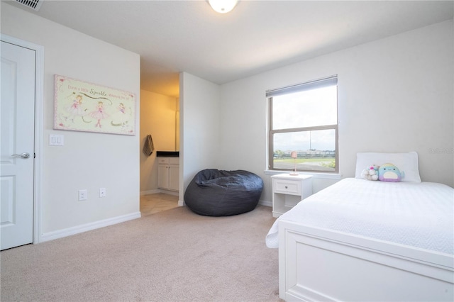 bedroom featuring ensuite bathroom and light colored carpet