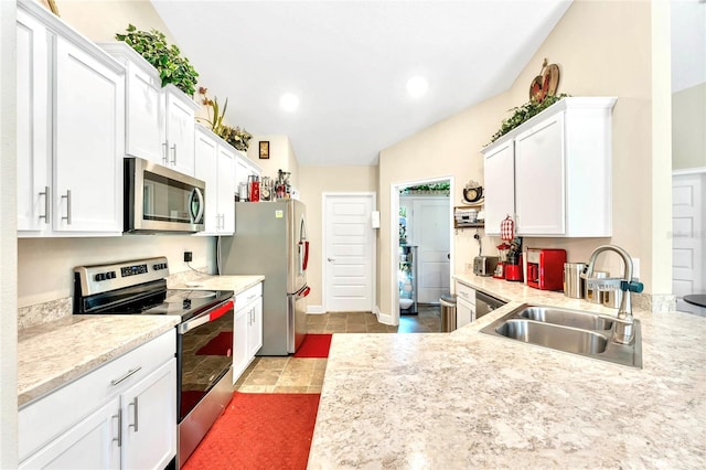 kitchen with light tile patterned floors, white cabinets, stainless steel appliances, vaulted ceiling, and sink