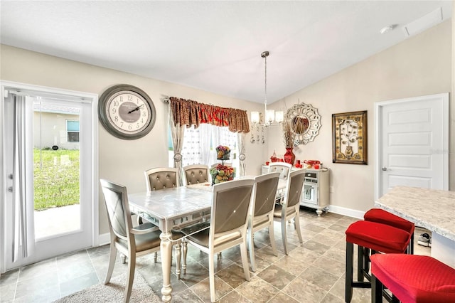 tiled dining space featuring a chandelier and vaulted ceiling