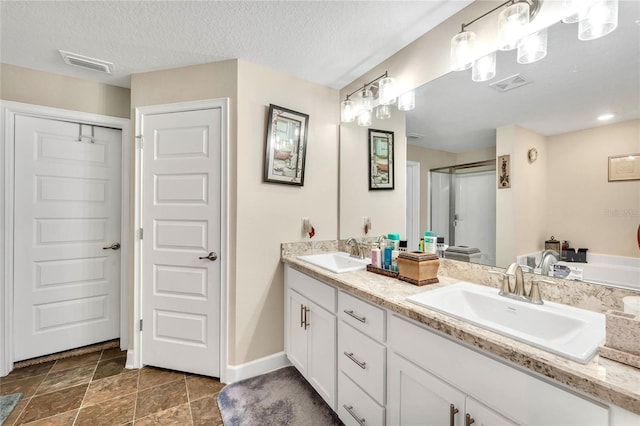 bathroom with tile patterned flooring, a textured ceiling, and dual bowl vanity