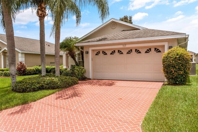 single story home with a garage and a front lawn