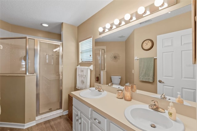 bathroom featuring walk in shower, double vanity, hardwood / wood-style floors, toilet, and a textured ceiling