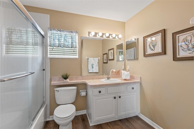 full bathroom with toilet, shower / bath combination with glass door, hardwood / wood-style floors, and vanity