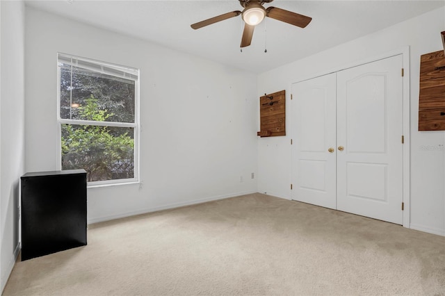 unfurnished bedroom featuring ceiling fan, light colored carpet, and a closet