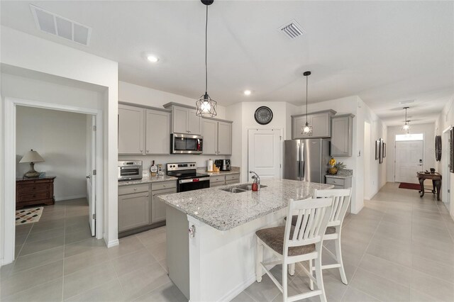 kitchen with light tile patterned flooring, stainless steel appliances, decorative light fixtures, and sink