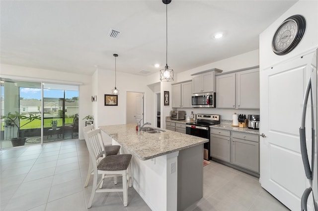 kitchen with range, light tile patterned flooring, a kitchen island with sink, gray cabinets, and decorative light fixtures