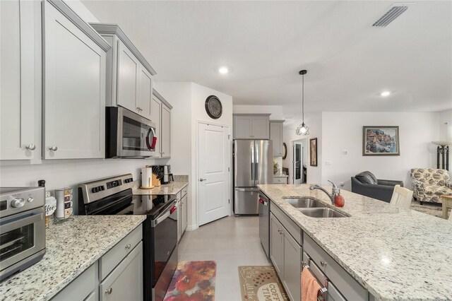 kitchen featuring appliances with stainless steel finishes, sink, light stone counters, gray cabinets, and light tile patterned floors