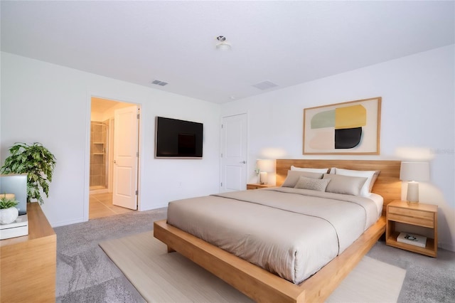 bedroom featuring connected bathroom and light colored carpet