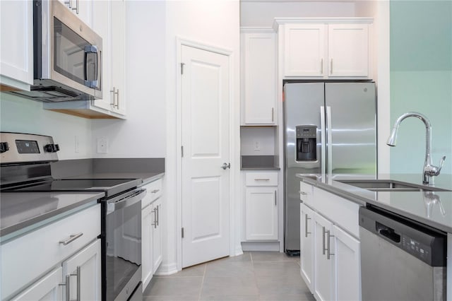 kitchen with white cabinetry, appliances with stainless steel finishes, sink, and light tile patterned floors